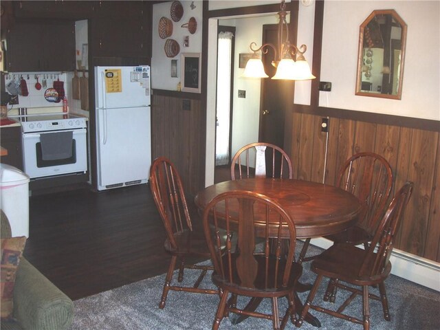 dining area featuring dark wood-type flooring, wainscoting, and an inviting chandelier