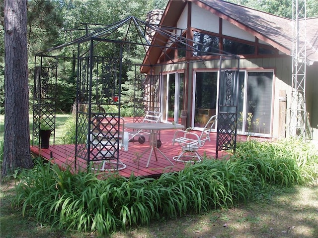 exterior space with roof with shingles, a wooden deck, and a sunroom