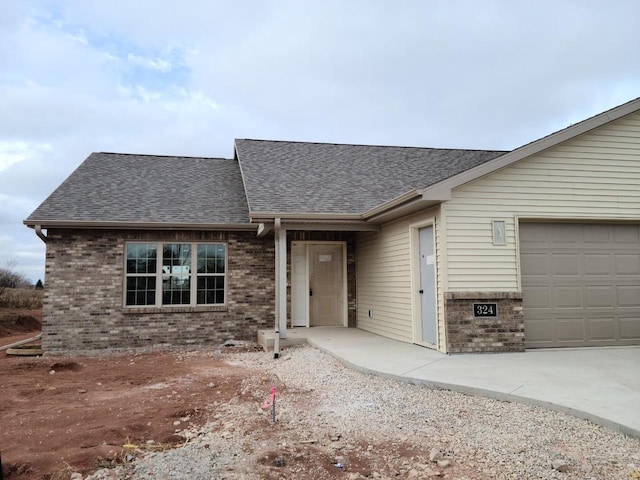 view of front of property with a garage, roof with shingles, and brick siding