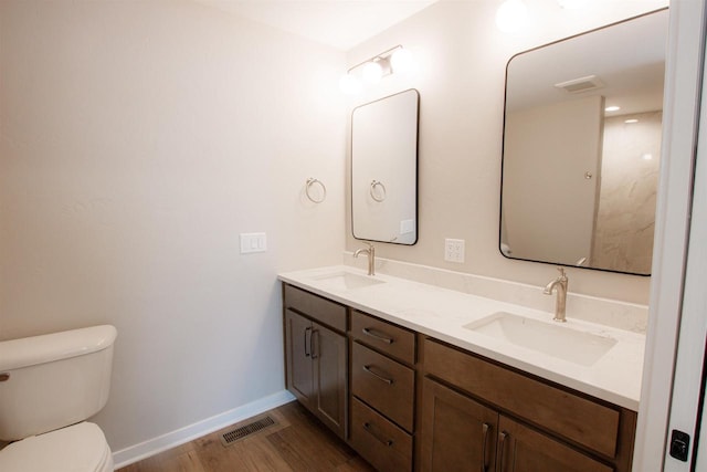 bathroom featuring toilet, wood finished floors, a sink, and visible vents