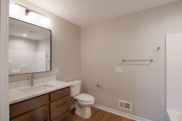 bathroom featuring visible vents, toilet, vanity, wood finished floors, and baseboards