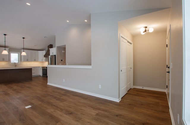 kitchen with white cabinetry, light countertops, freestanding refrigerator, dark wood finished floors, and decorative light fixtures