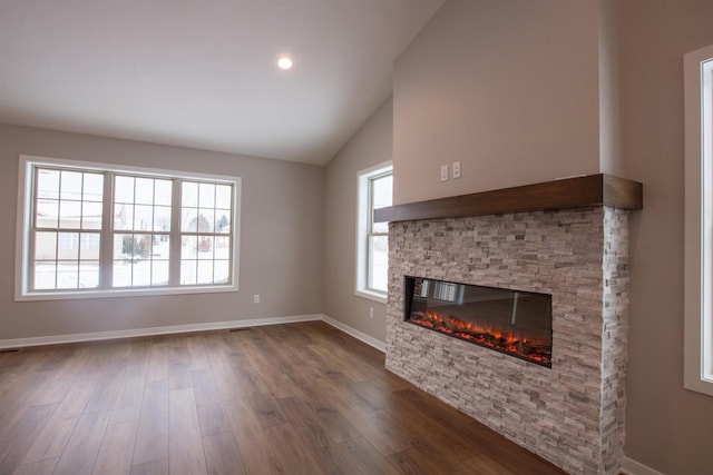 unfurnished living room with vaulted ceiling, a fireplace, baseboards, and wood finished floors