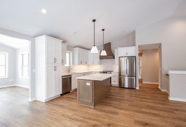 kitchen featuring a center island, light countertops, hanging light fixtures, appliances with stainless steel finishes, and premium range hood