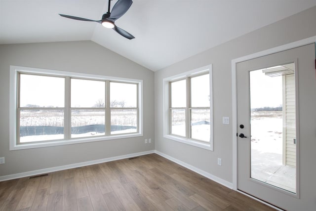 spare room with ceiling fan, visible vents, baseboards, vaulted ceiling, and light wood finished floors