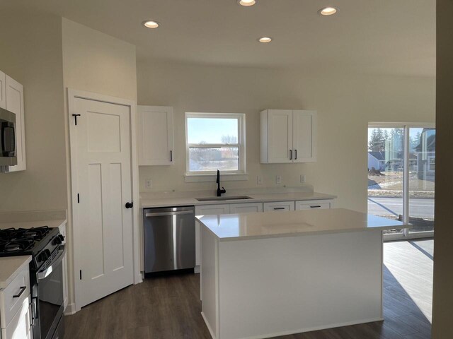 kitchen featuring hanging light fixtures, a kitchen island, white cabinetry, appliances with stainless steel finishes, and hardwood / wood-style floors