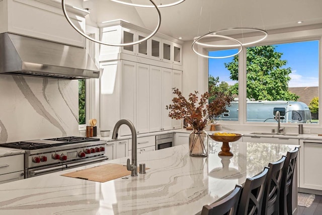 interior space with ventilation hood, white cabinetry, stainless steel range, and light stone countertops