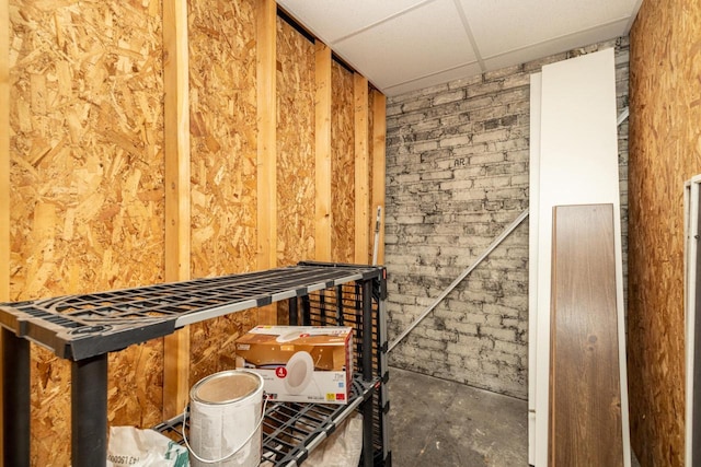 interior space featuring brick wall and a drop ceiling