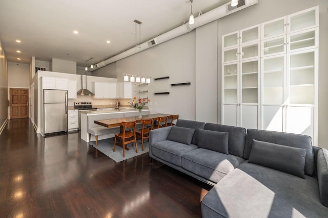 living room with rail lighting, a towering ceiling, and dark hardwood / wood-style flooring