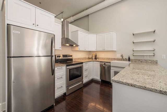 kitchen featuring appliances with stainless steel finishes, wall chimney exhaust hood, light stone counters, white cabinets, and sink