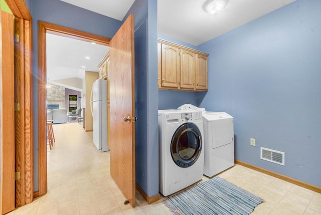 laundry room with a fireplace, washing machine and dryer, and cabinets