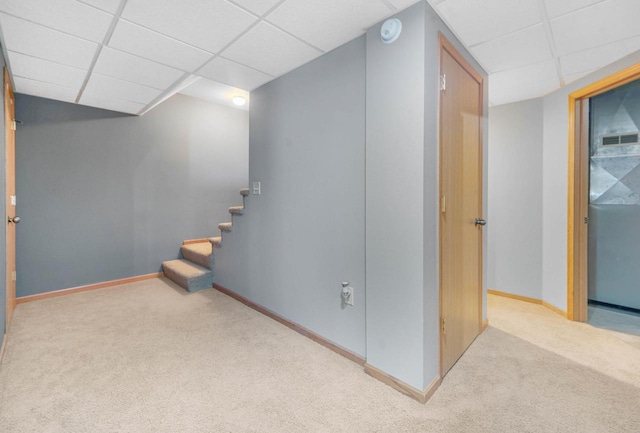 basement featuring light colored carpet and a drop ceiling