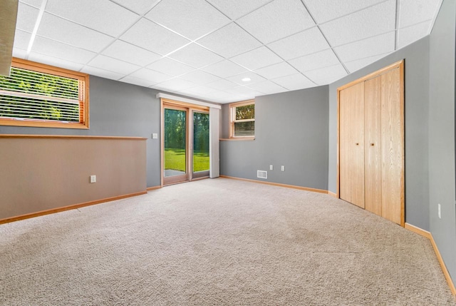 carpeted empty room featuring a drop ceiling