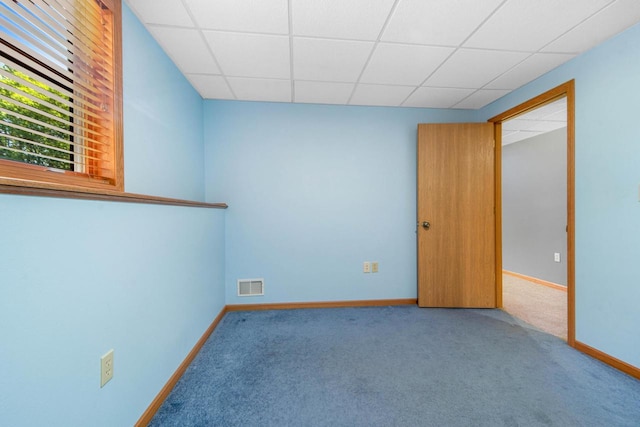 carpeted spare room with a drop ceiling