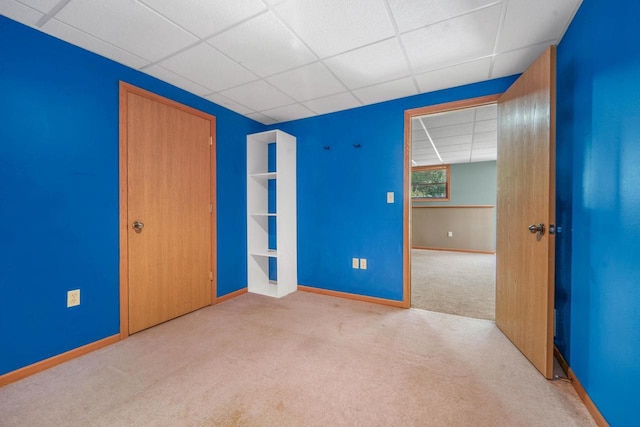 unfurnished bedroom featuring light colored carpet, a closet, and a drop ceiling