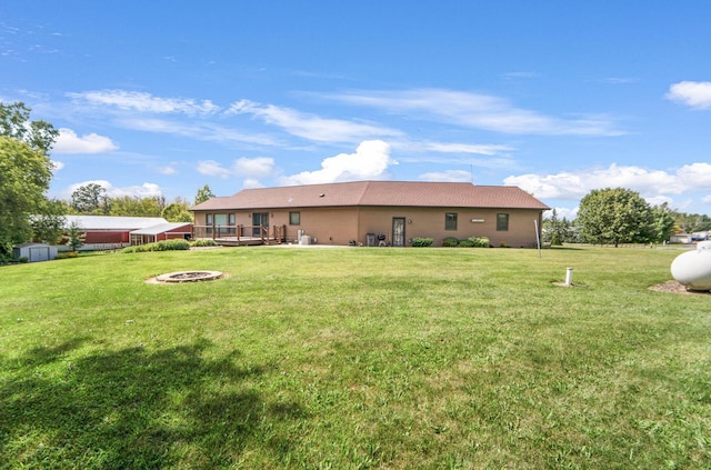 back of house with a yard, a deck, and a fire pit