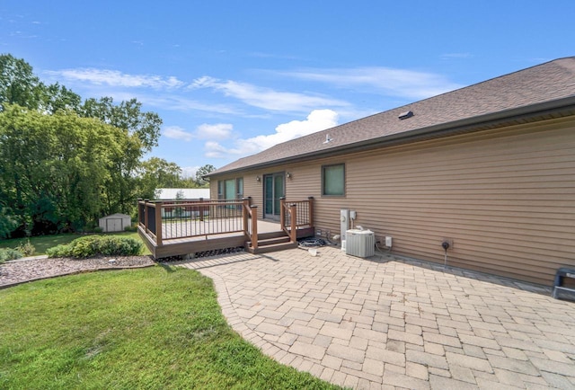 rear view of property with a patio area, central AC unit, a yard, a wooden deck, and a storage unit