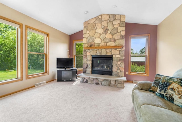 carpeted living room with lofted ceiling, a stone fireplace, and a healthy amount of sunlight