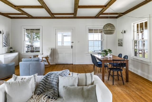 living room featuring beamed ceiling, coffered ceiling, and light hardwood / wood-style flooring