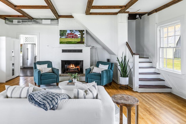 living room featuring a fireplace, light hardwood / wood-style flooring, beamed ceiling, and coffered ceiling