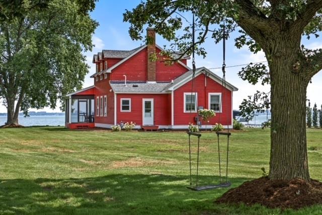 rear view of property featuring a water view and a lawn