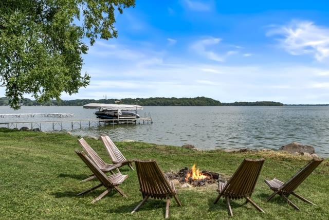 dock area featuring a lawn, a fire pit, and a water view