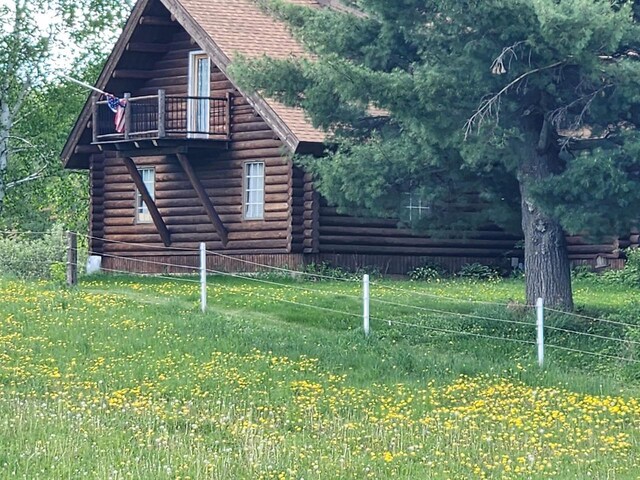 W6769 County Road D, Sheldon, WI 54766 - view of side of property featuring log siding, a shingled roof, and a balcony