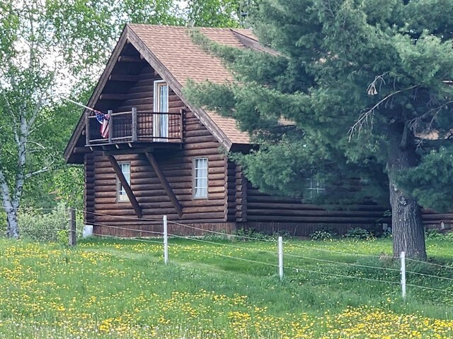 W6769 County Road D, Sheldon, WI 54766 - view of side of home with log siding, a balcony, and a shingled roof