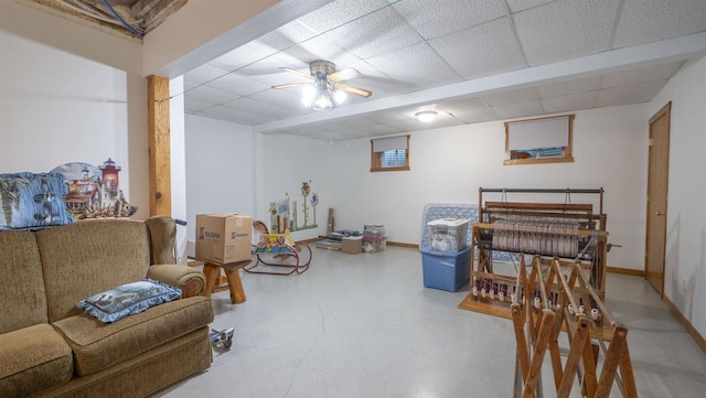 living area featuring ceiling fan, concrete floors, and a drop ceiling