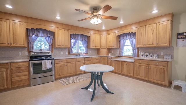 kitchen with a wealth of natural light, ceiling fan, decorative backsplash, and stainless steel range with electric stovetop