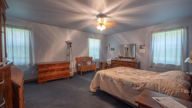 bedroom featuring ceiling fan, dark colored carpet, and multiple windows