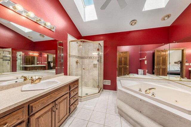 bathroom featuring ceiling fan, independent shower and bath, lofted ceiling with skylight, vanity, and tile patterned floors