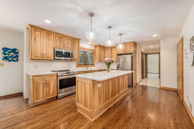 kitchen with hardwood / wood-style floors, sink, appliances with stainless steel finishes, decorative backsplash, and a kitchen island