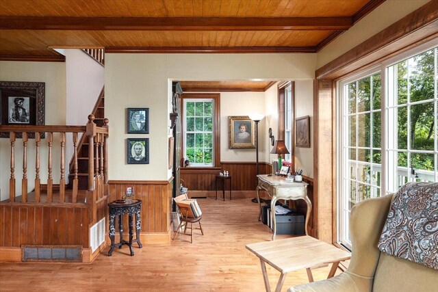 living area featuring beam ceiling, light wood-type flooring, wood ceiling, and wood walls