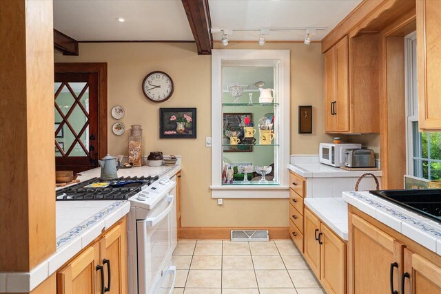 kitchen featuring rail lighting, light tile patterned floors, white appliances, and tile countertops