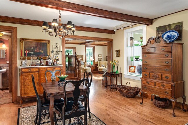 dining area featuring a notable chandelier, beamed ceiling, sink, and hardwood / wood-style floors