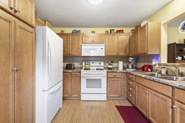 kitchen featuring white appliances, light hardwood / wood-style floors, sink, and a textured ceiling