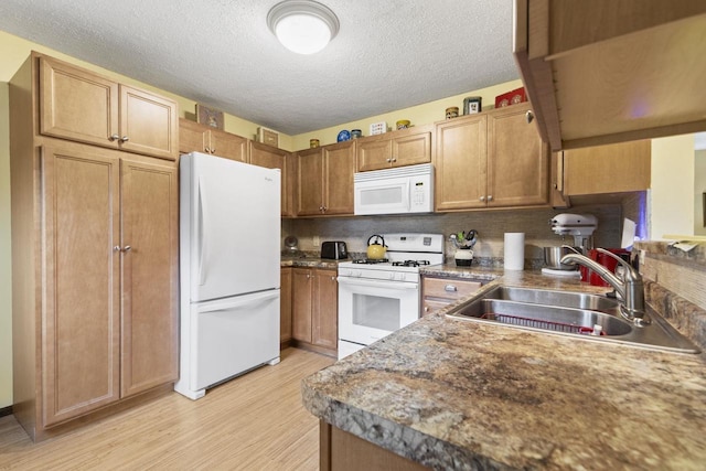 kitchen with light hardwood / wood-style floors, sink, white appliances, tasteful backsplash, and a textured ceiling