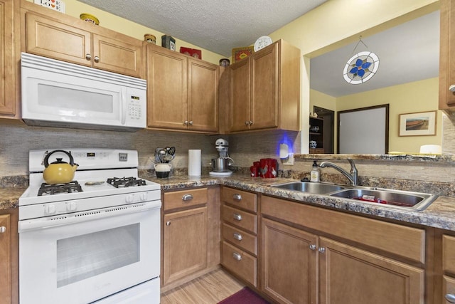 kitchen with white appliances, sink, light wood-type flooring, a textured ceiling, and tasteful backsplash