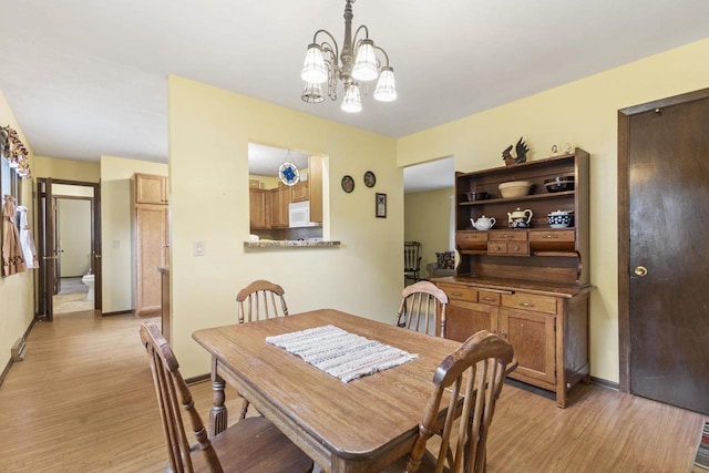 dining area with light hardwood / wood-style floors and a chandelier