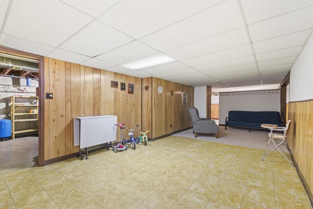 basement with wood walls and a drop ceiling