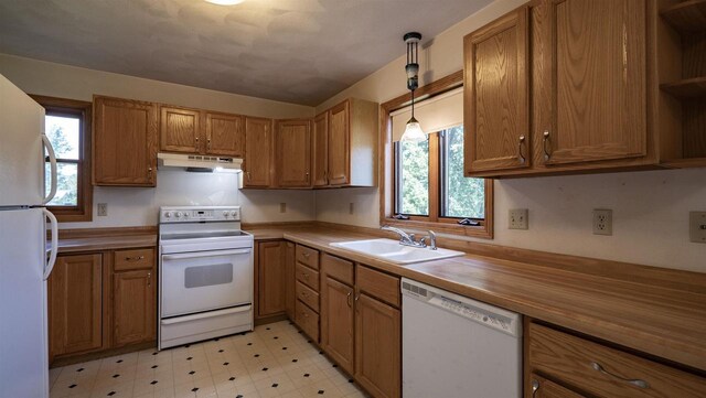 kitchen with light tile patterned floors, sink, hanging light fixtures, and white appliances