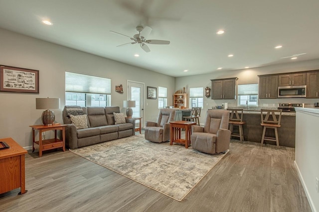 living room with light hardwood / wood-style flooring and ceiling fan