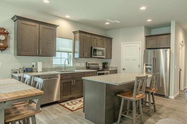 kitchen featuring sink, stainless steel appliances, light stone counters, and dark brown cabinetry