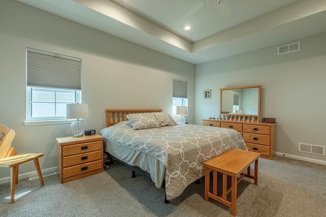 carpeted bedroom featuring a raised ceiling and ceiling fan