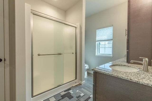 bathroom with vanity, an enclosed shower, toilet, and hardwood / wood-style floors