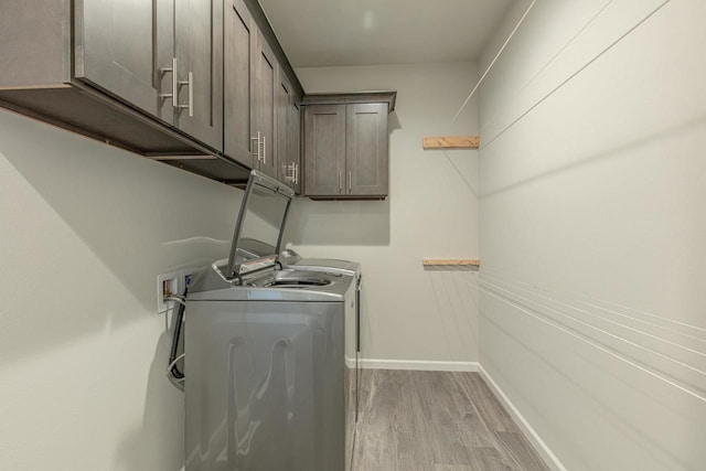 laundry area featuring cabinets, light hardwood / wood-style flooring, and washer and clothes dryer