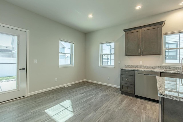 kitchen featuring dark brown cabinetry, light stone countertops, stainless steel dishwasher, light hardwood / wood-style floors, and sink