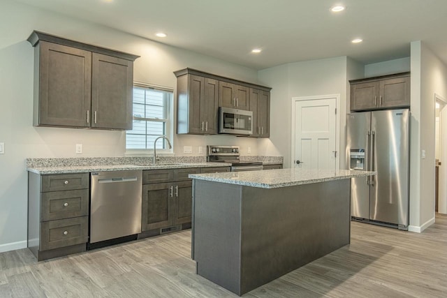 kitchen with stainless steel appliances, a center island, light hardwood / wood-style floors, sink, and dark brown cabinets