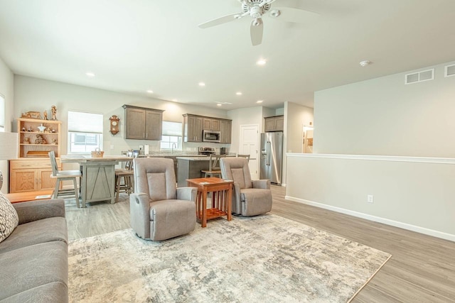 living room with sink, ceiling fan, and light hardwood / wood-style floors